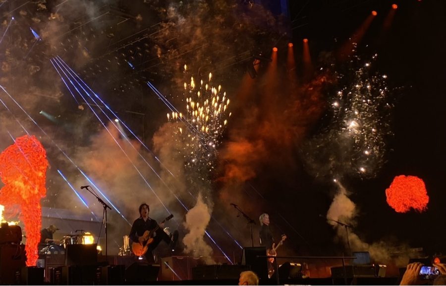 Fire, strobe lights, smoke, and fireworks are set off at a concert, and the audience cheers.