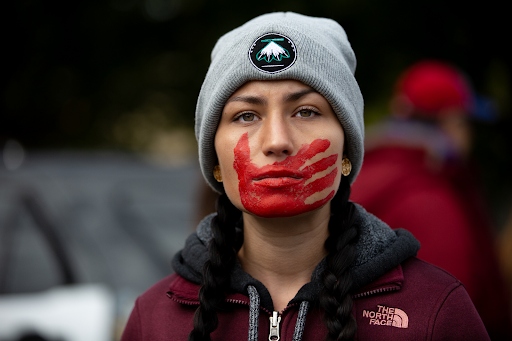 A red handprint over the mouth is used by the MMIW movement and represents the silenced voices of native women affected by crime. 