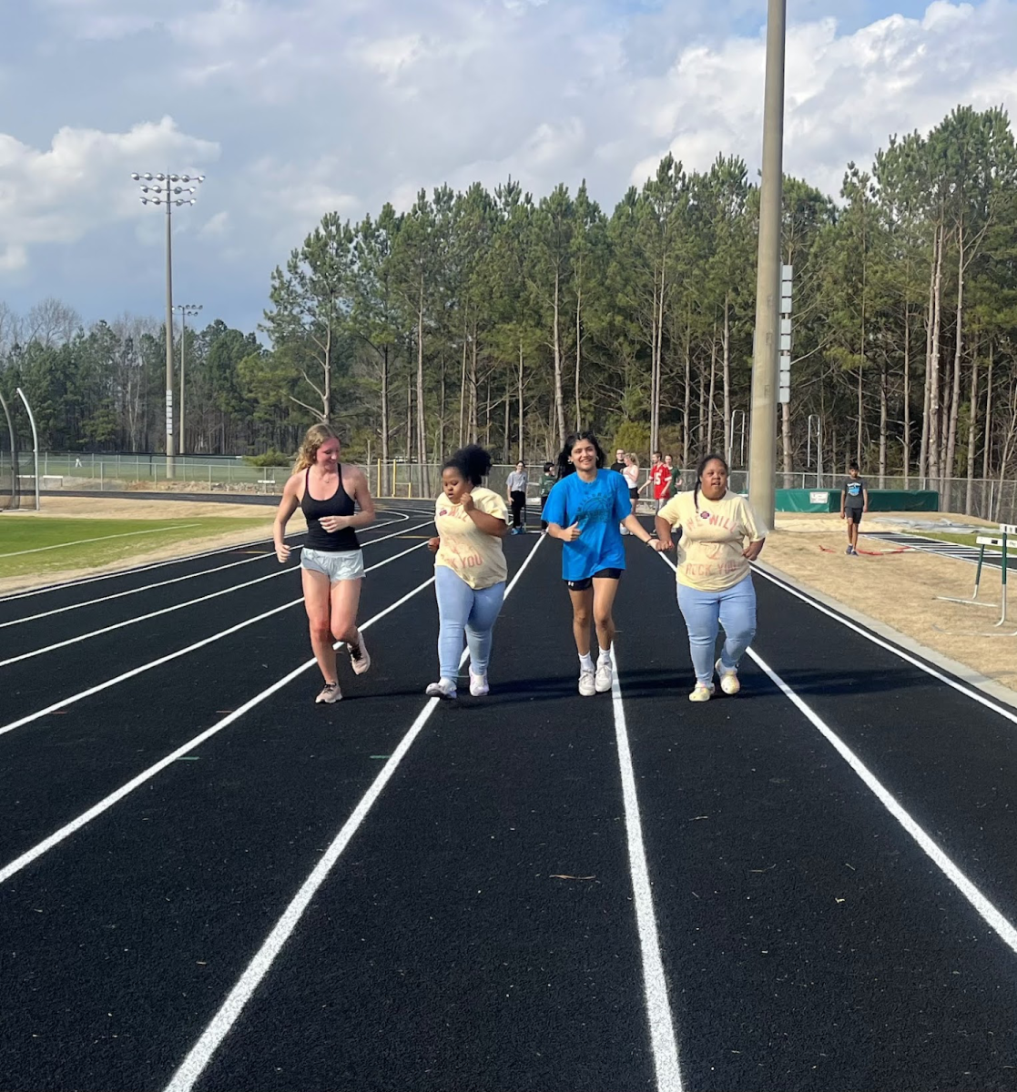Warming up means a fun jog around the track with friends. With a meet coming up, practice to stay in between the white lines becomes critical. Photo used with permission from Laura Bunn.