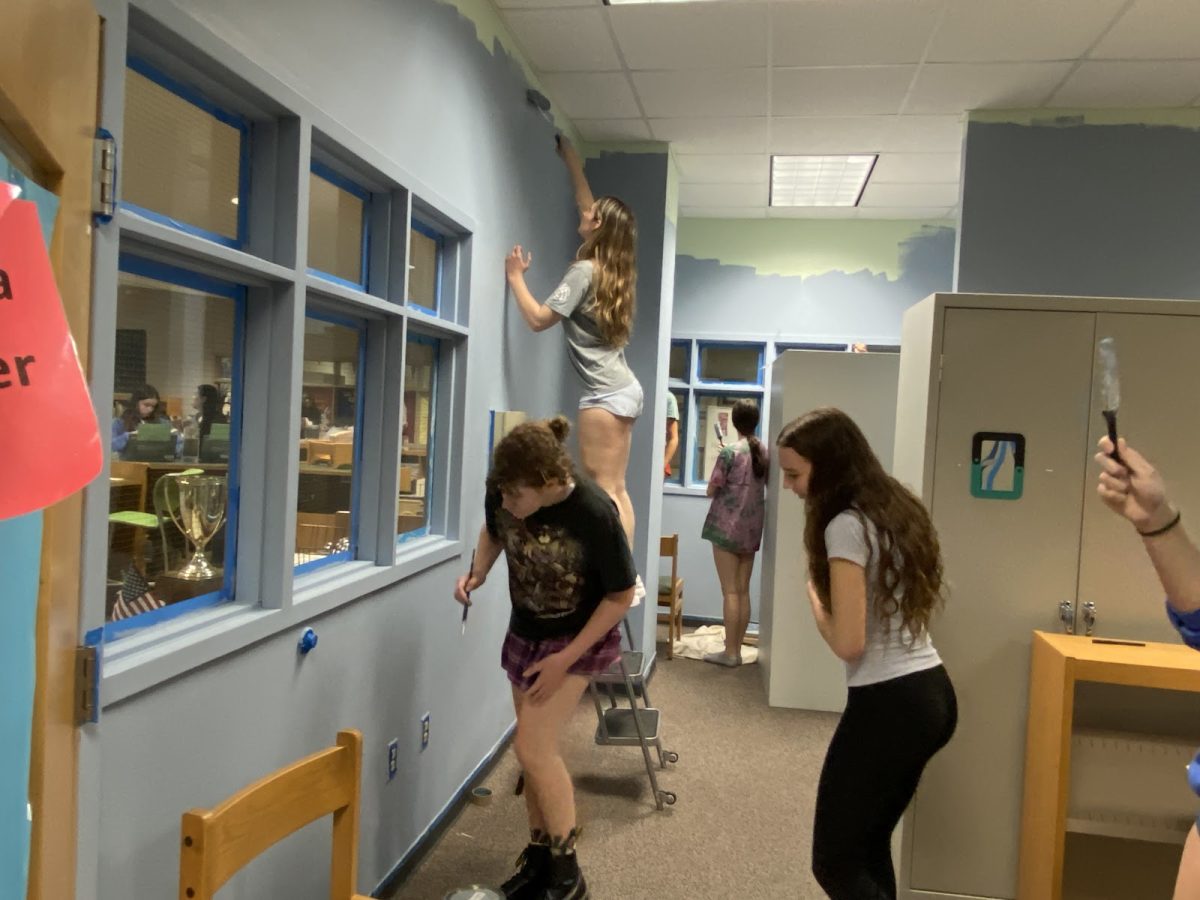 Interior design students work together to repaint the walls of the old storage room.