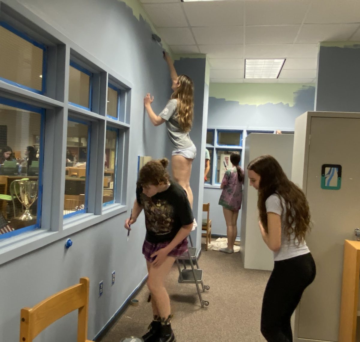 Interior design students work together to repaint the walls of the old storage room.