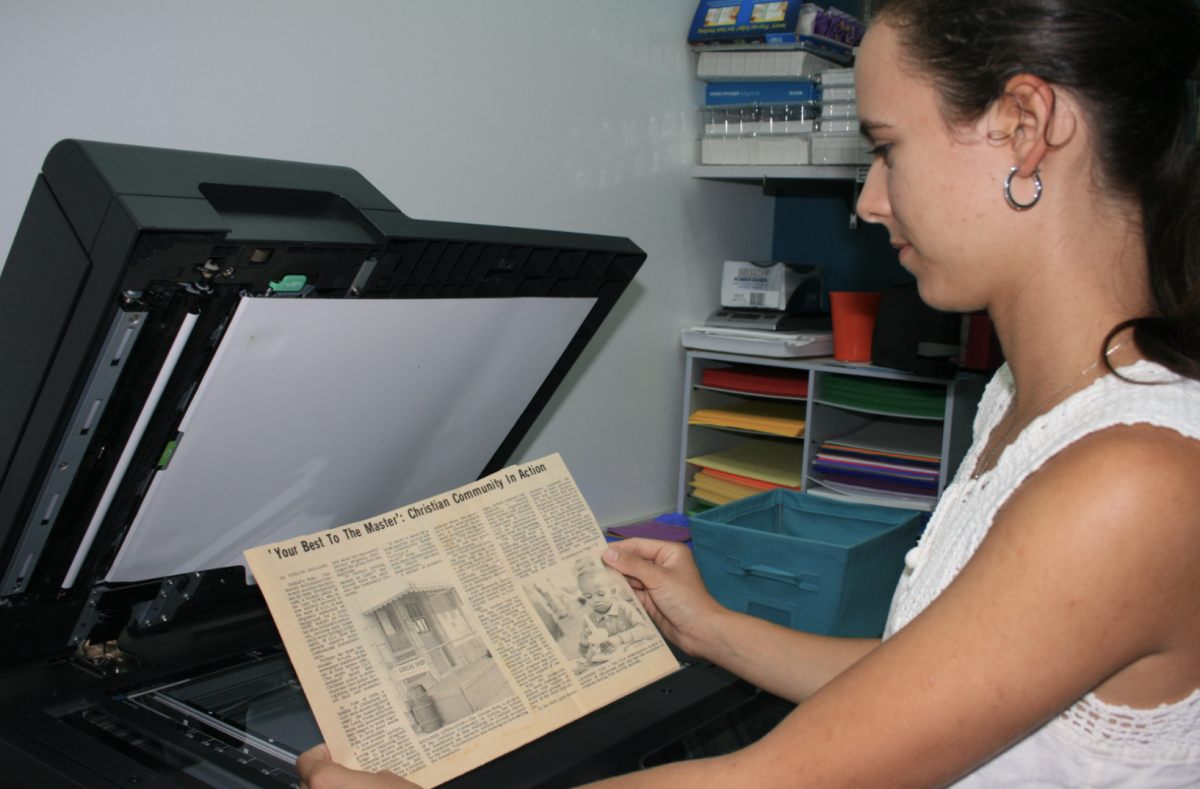 Katie Biddle ('25) scans a newspaper clipping profiling Dorcas from several decades ago. This is one document of hundreds that the Green Hope senior is working on digitizing. 