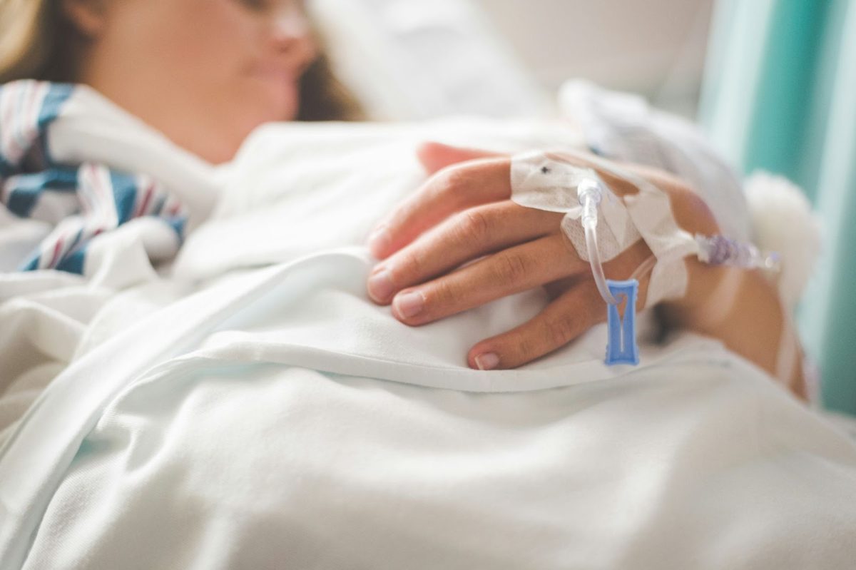 A patient with an IV line connected to their hand, receiving fluid during an operation. Photo used with permission from Stephen Andrews via Unsplash
