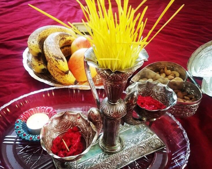 Set of Jamara (yellow grass) with a side of tika (red colored rice) and some prasad (fruits).