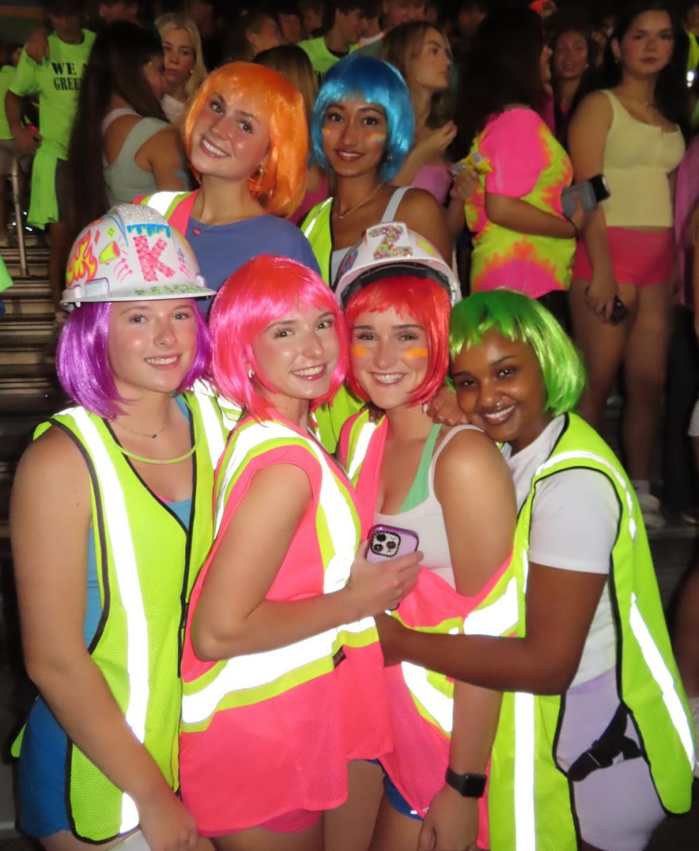 Green Hope seniors pose in their creative outfits at the"Neon Out” neon out game against Apex Friendship High School. Photo used with permission from the Falcon Frenzy on instagram.