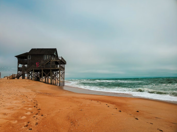 An old wooden house in Rodanthe, right on the beach as ocean waves come closer to the house. Photo used with permission from Raymond Kotewicz on Unsplash.