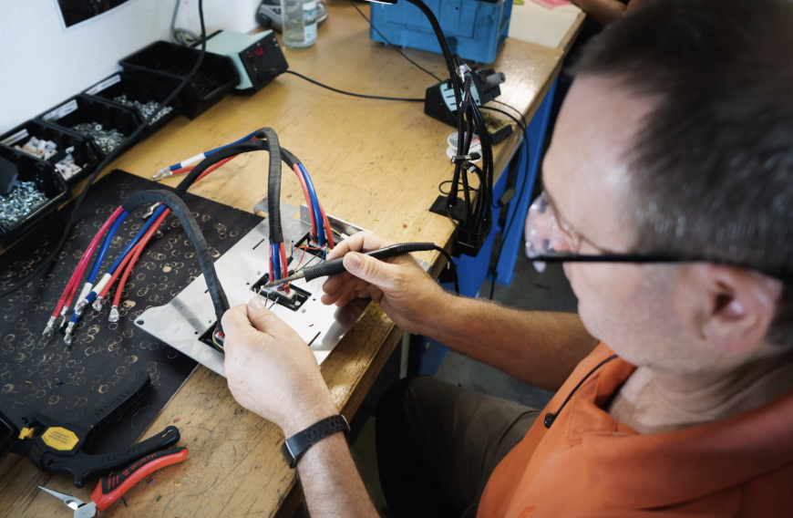 Picture of a man in trade school soldering a wire harness. Photo used with permission from Kumpan Electric via Unsplash.