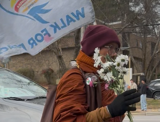 A monk carries gifted flowers and a flag sporting the "Walk For Peace" message through Cary, NC on a cold January day. Photo used with permission from Jenna Abernathy.