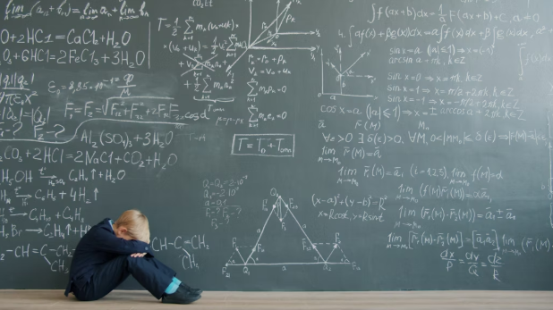 A student sits overwhelmed as complex math formulas fill the board in front of him. Photo used with permission from Vitaly Gariev via Unsplash.
