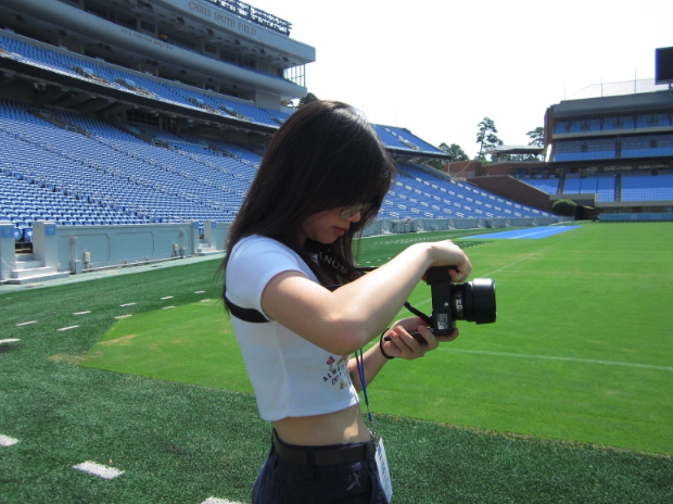 An Vu (‘26) poses with her camera on the grounds of Kenan Memorial Stadium at the University of North Carolina at Chapel Hill.