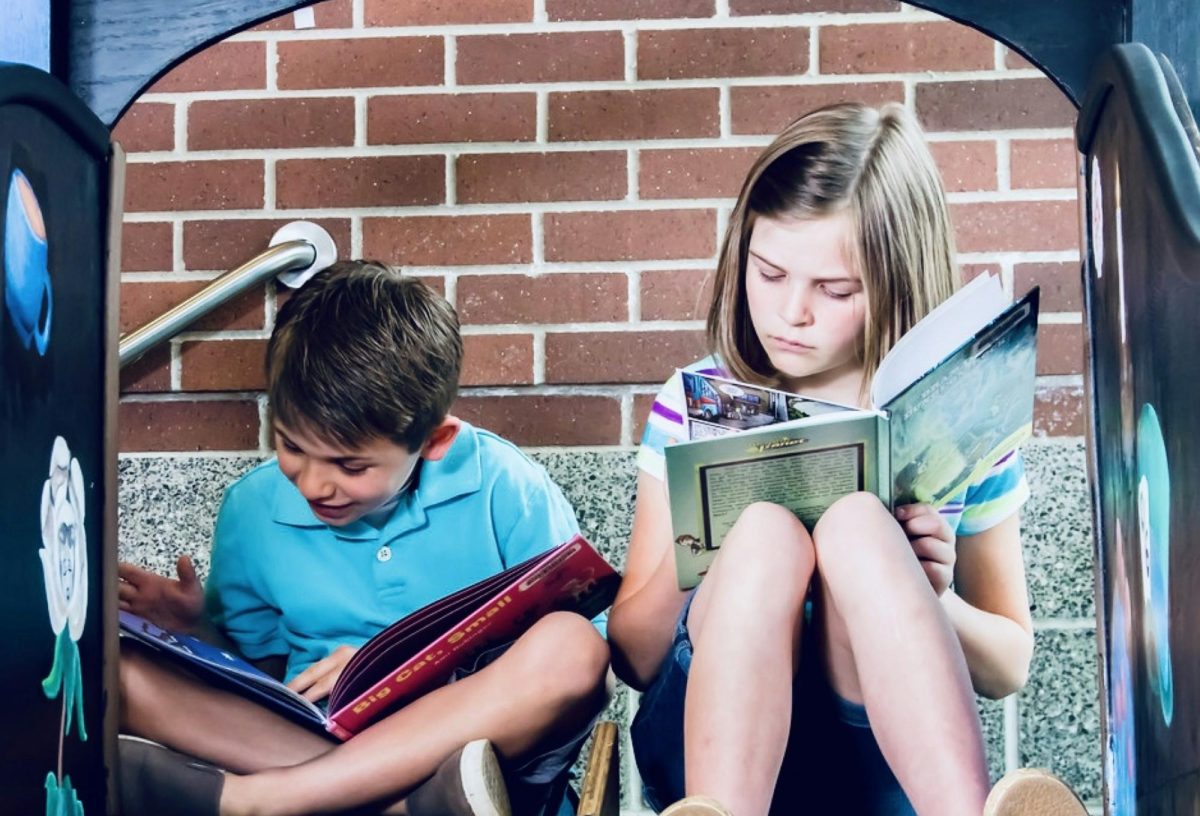 Two children reading a book while on a slide. Reading has various benefits for both one's mental health and cognitive functioning. Photo used with permission by Adam Winger on Unsplash.