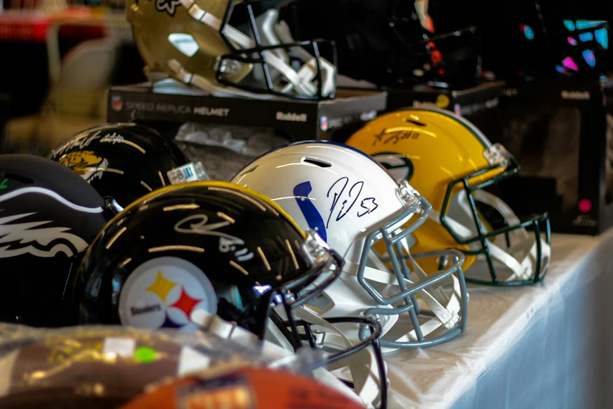 A row of NFL helmets sitting on a table. Photo used with permission from Jonathan Olsen-Koziol via Unsplash.