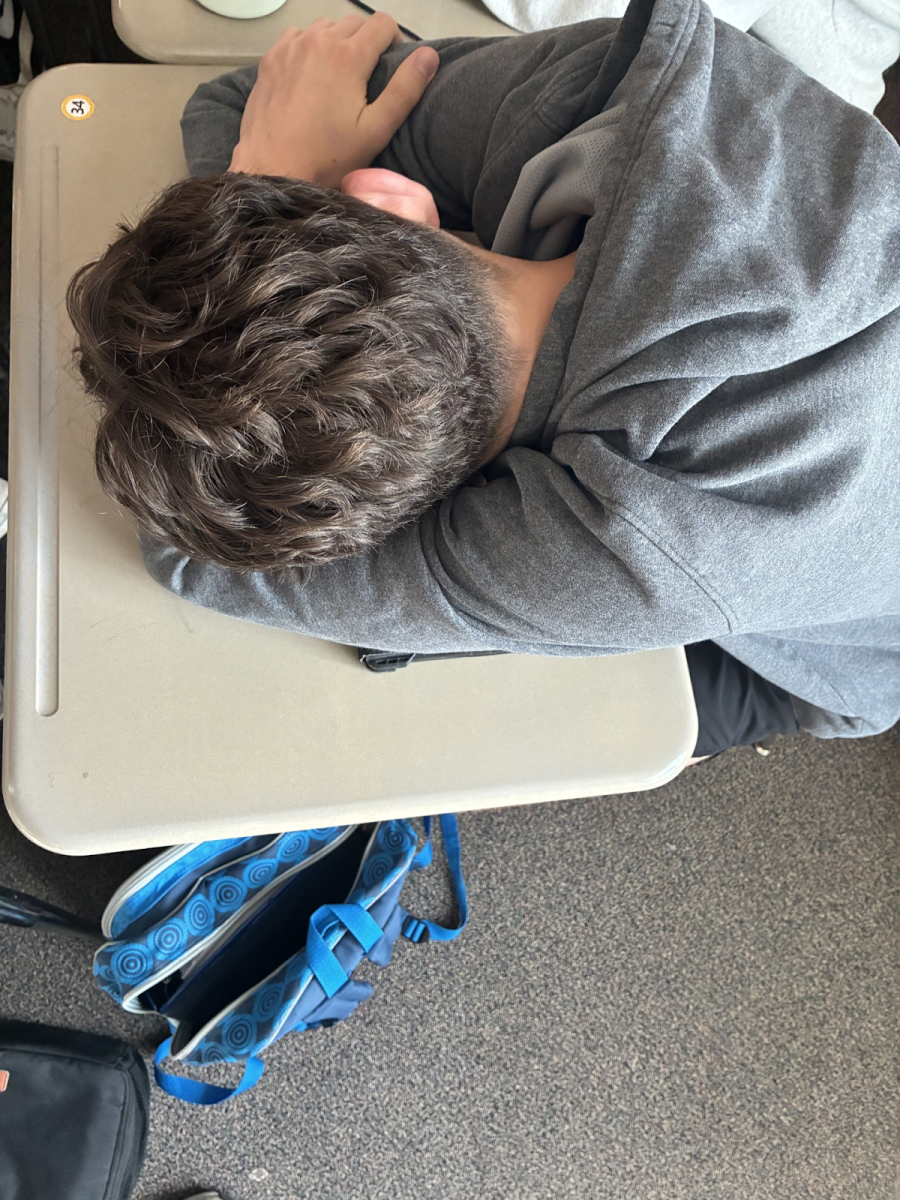 A student sleeping on his desk. If schools start later, children may be able to get more sleep--- but that is not a guarantee. 